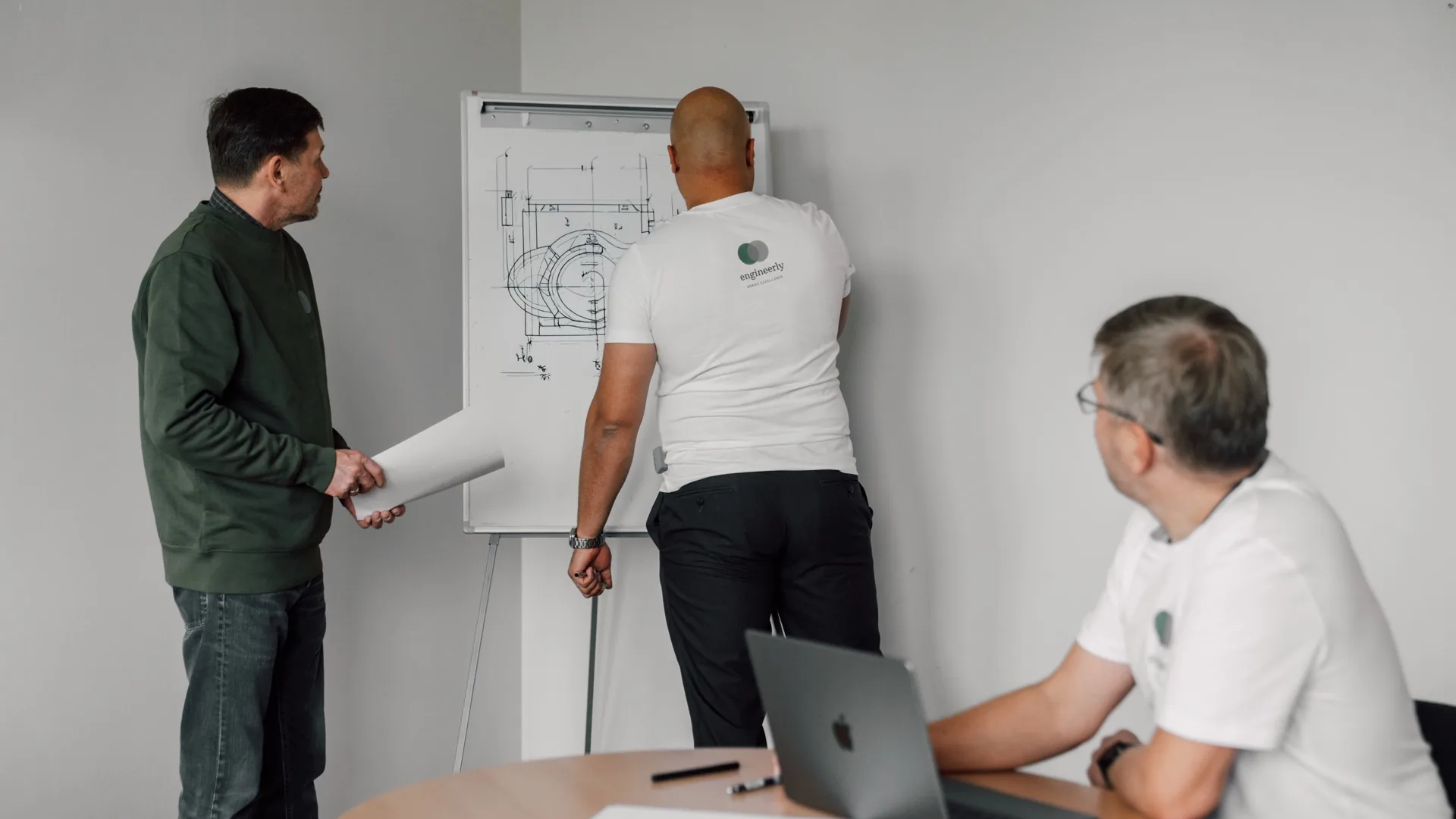 Engineers discussing technical work at a whiteboard.